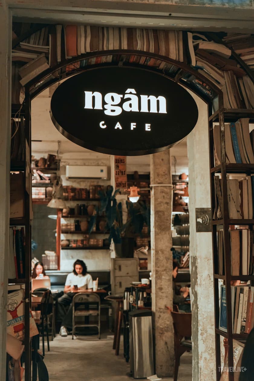 The oval ngâm CAFE sign glowing at night