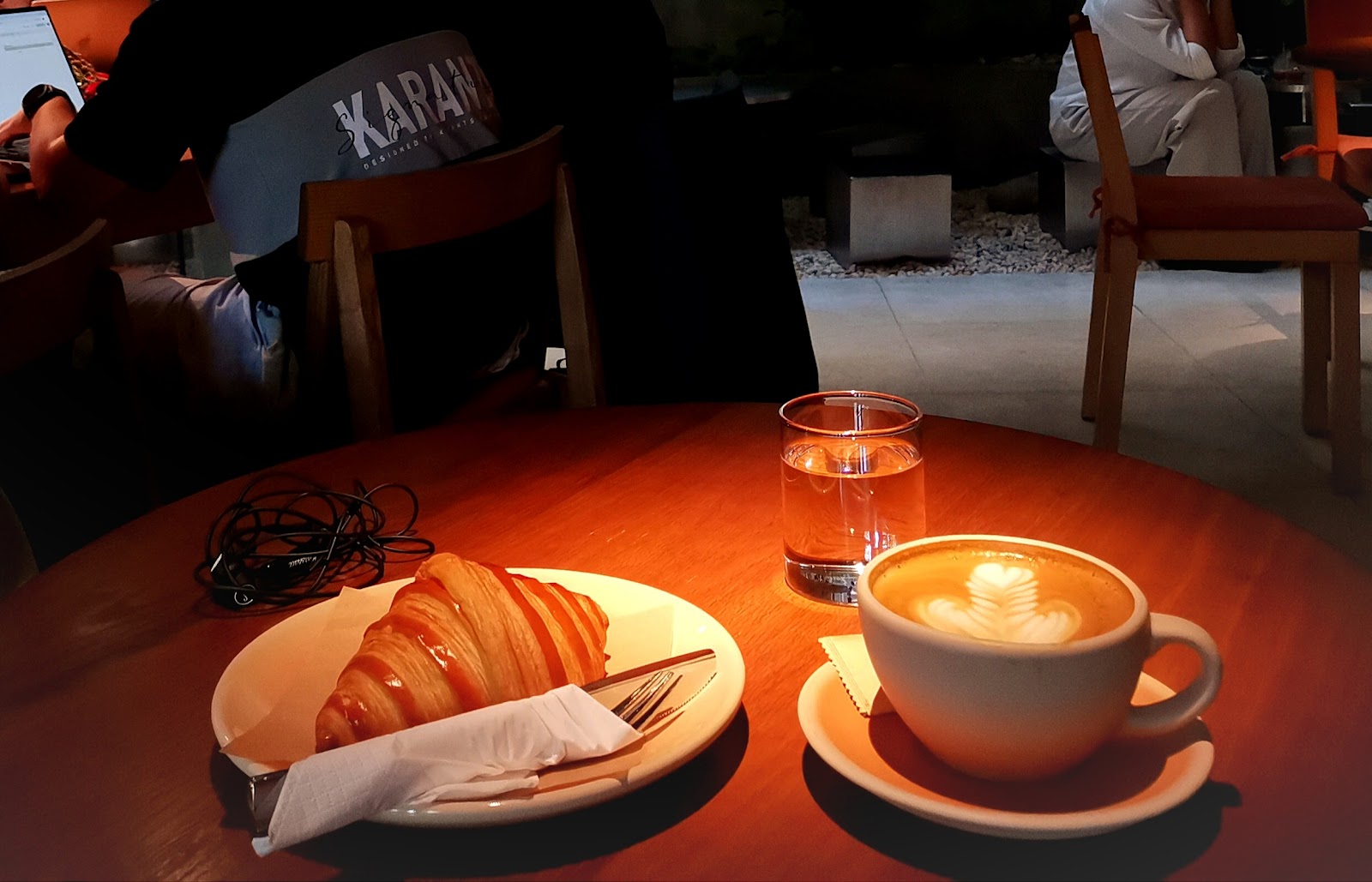 Latte art and croissant under warm evening light