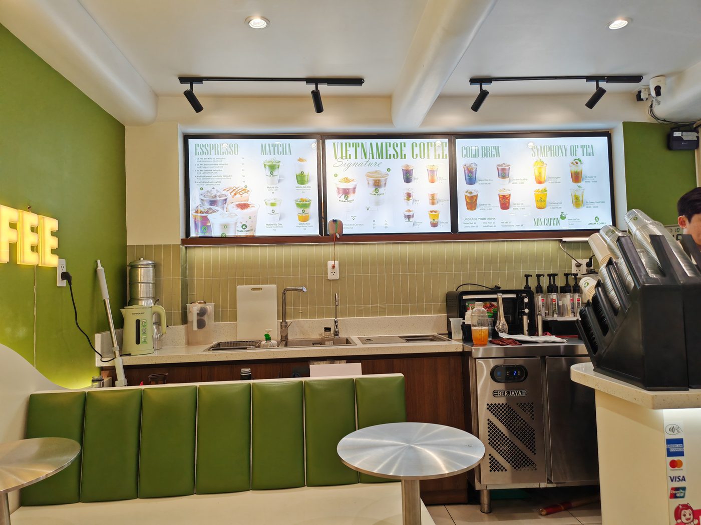 Không gian Anam coffee: tường xanh, chữ COFFEE neon, bảng menu đèn