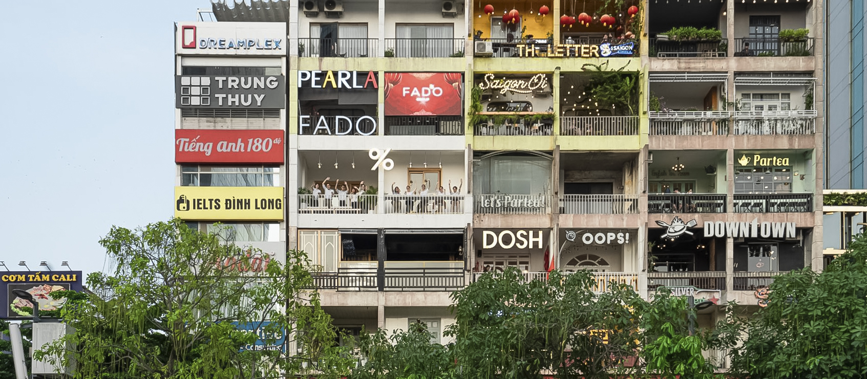 Mặt tiền The Cafe Apartments, 42 Nguyễn Huệ về đêm — dấu % neon sáng trên tầng 4