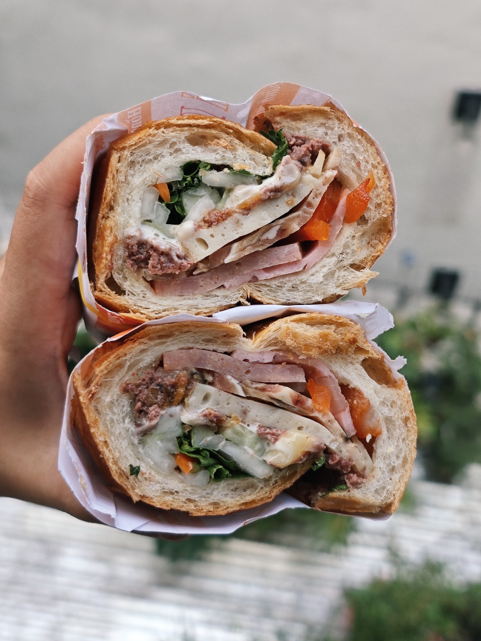 Handheld mixed bánh mì — the filling-packed cross-section