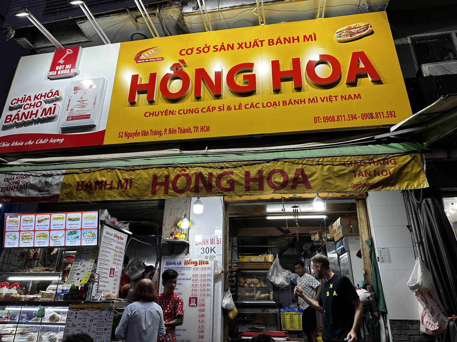 The shop at night — the yellow signboard lit