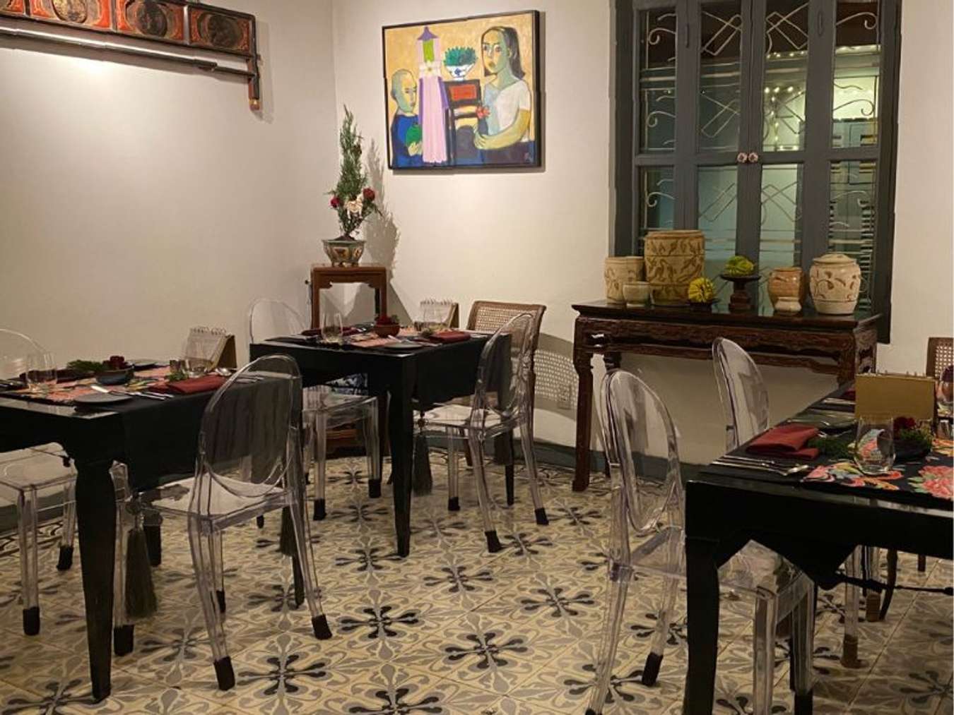 Phòng ăn với bàn tối, ghế trong suốt và gạch bông