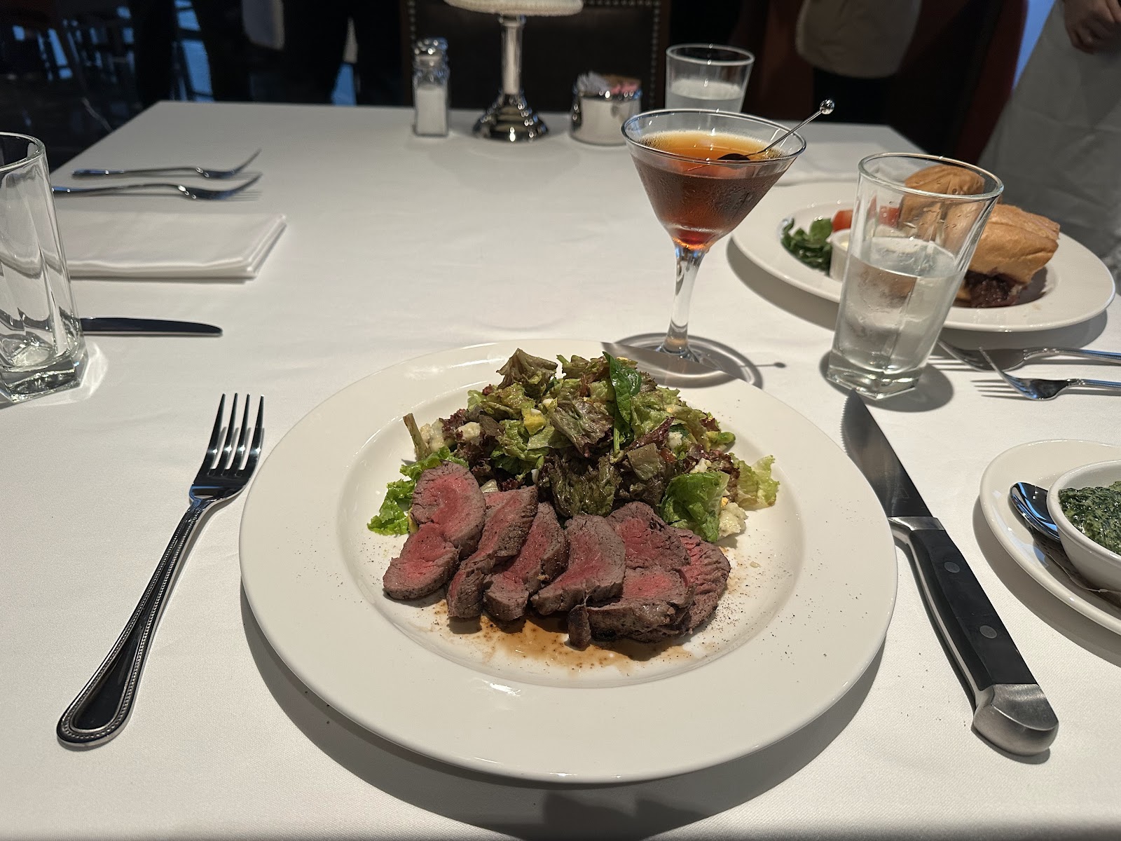 Sliced beef tenderloin with salad and a cocktail