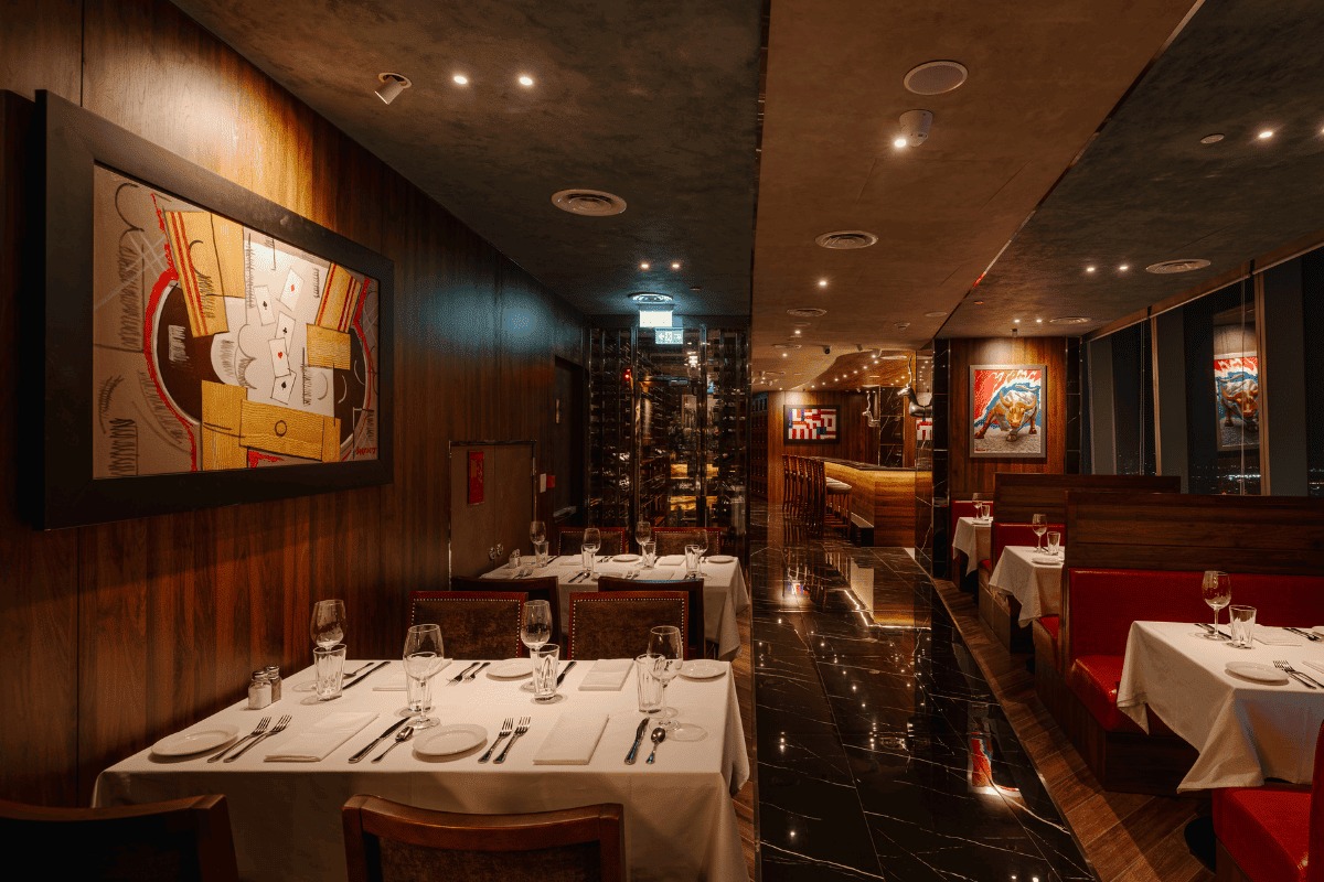 The Capital Grille's dark wood-panelled dining room with red leather banquettes