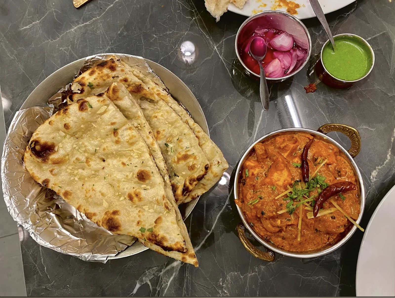 Garlic naan and chicken curry in a copper handi