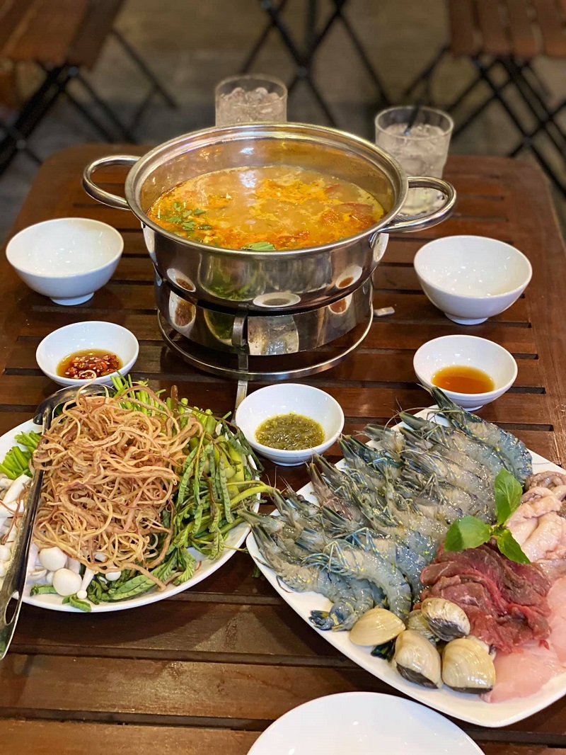 Tom Yum hotpot on the wooden table, with shrimp, beef and greens for the pot