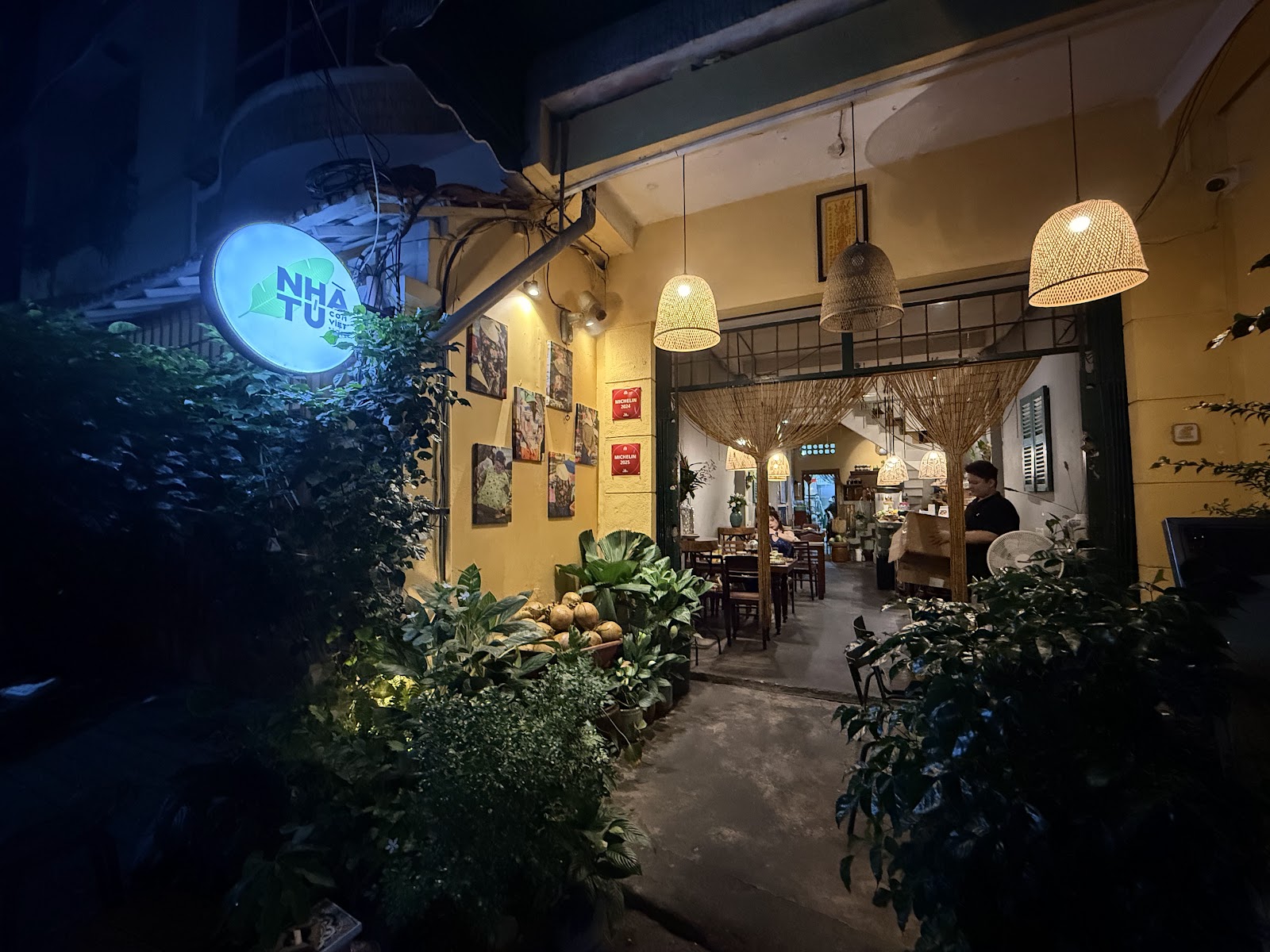 Cơm Nhà Tú storefront at night, sign lit up