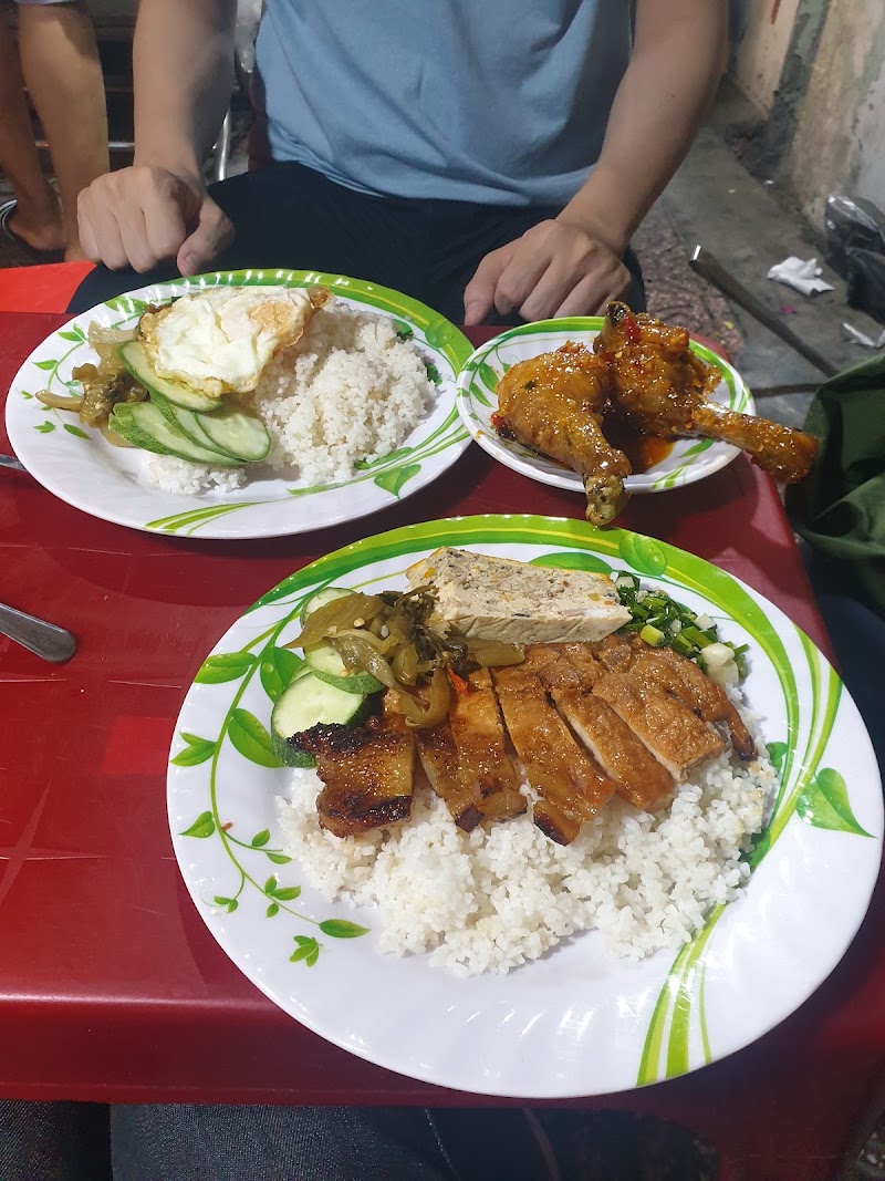 Dĩa cơm sườn bì chả trên bàn nhựa đỏ — dĩa trắng viền lá xanh