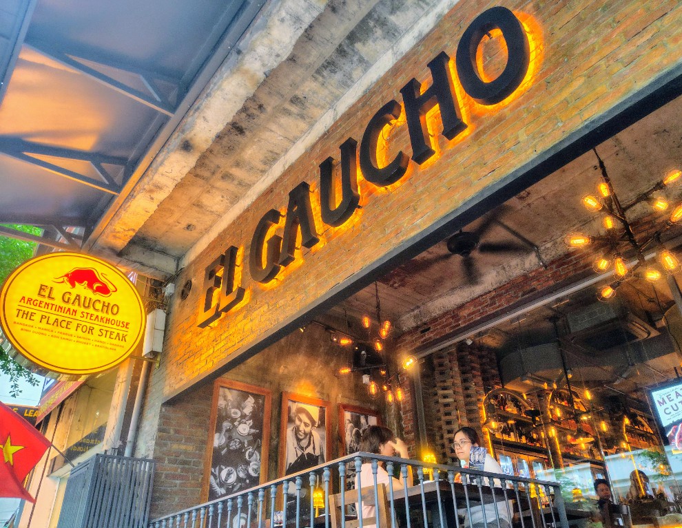 The yellow "EL GAUCHO — ARGENTINIAN STEAKHOUSE — THE PLACE FOR STEAK" blade sign over the sidewalk