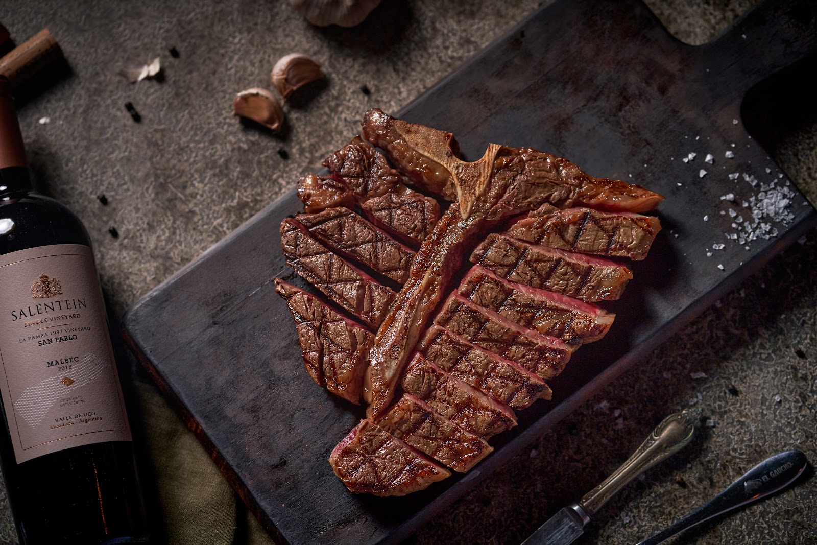 Sliced T-bone on the board with the bottle of Salentein Malbec
