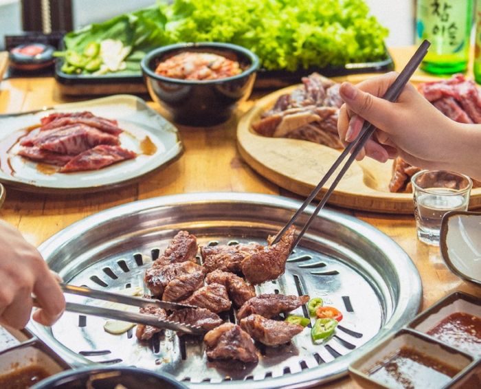 Chopsticks lifting meat off the grill