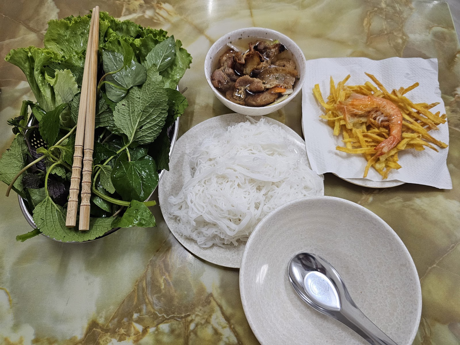 The full bún chả set — the grilled-pork dipping bowl, white vermicelli, fresh greens, bamboo chopsticks, the crisp fried side