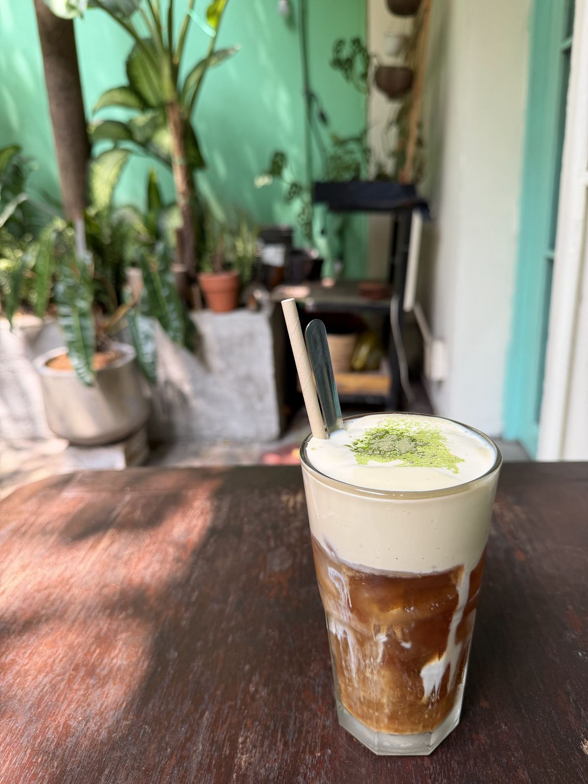 Hoi Beo Cafe — thick-foam drink dusted with matcha, hostel courtyard (Apr 2026)
