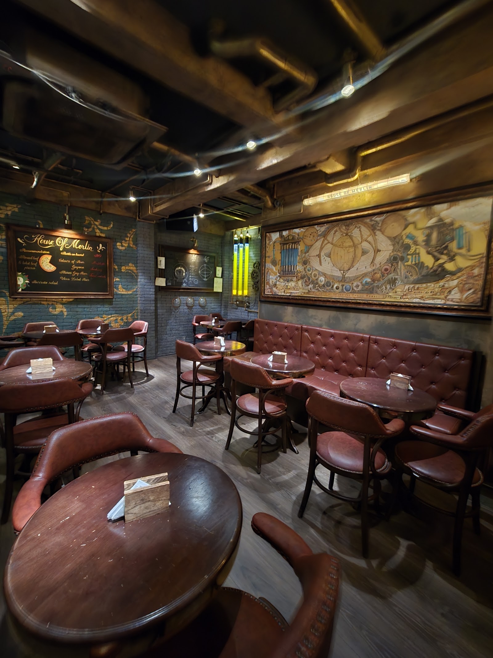 Tường quầy bar — lan can đồng thau, chai phát sáng, chi tiết bánh răng