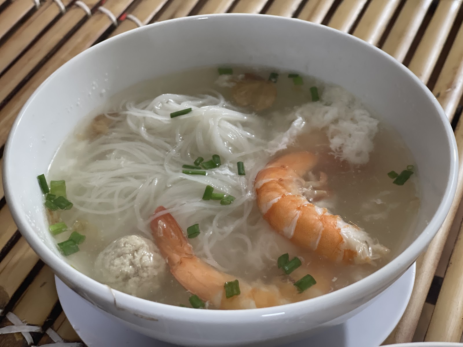 Clear-broth hu tieu with big shrimp and a meatball, on the bamboo mat — a guest's photo