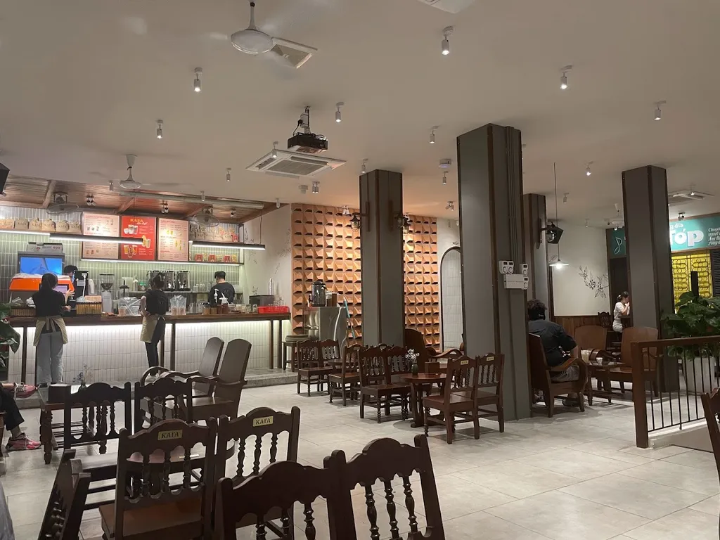 Quầy pha chế mở với bảng menu treo cao, ghế gỗ KAFA phía trước