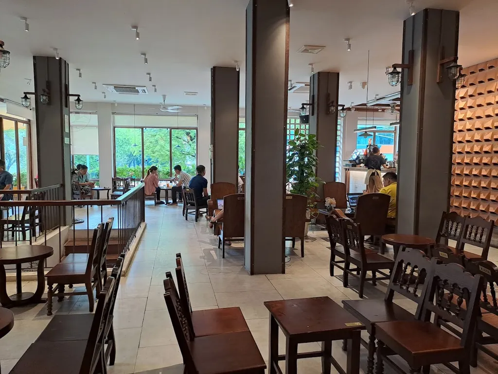 Sảnh chính ban ngày với hàng cột, bàn ghế gỗ và quầy pha chế