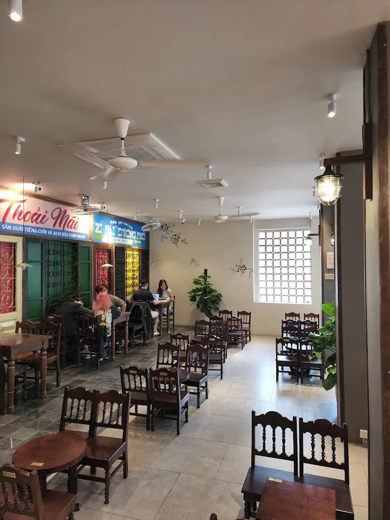 Tầng trên thoáng đãng với bàn ghế gỗ, cửa sổ lấy sáng