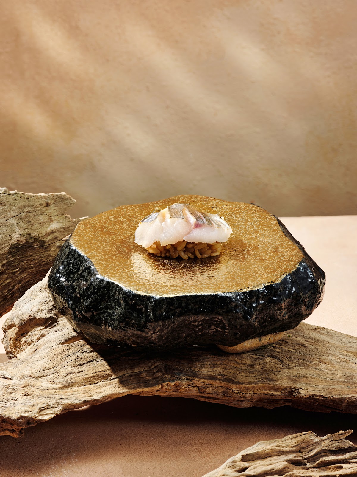 Một miếng nigiri trên đĩa đá, trên gỗ lũa