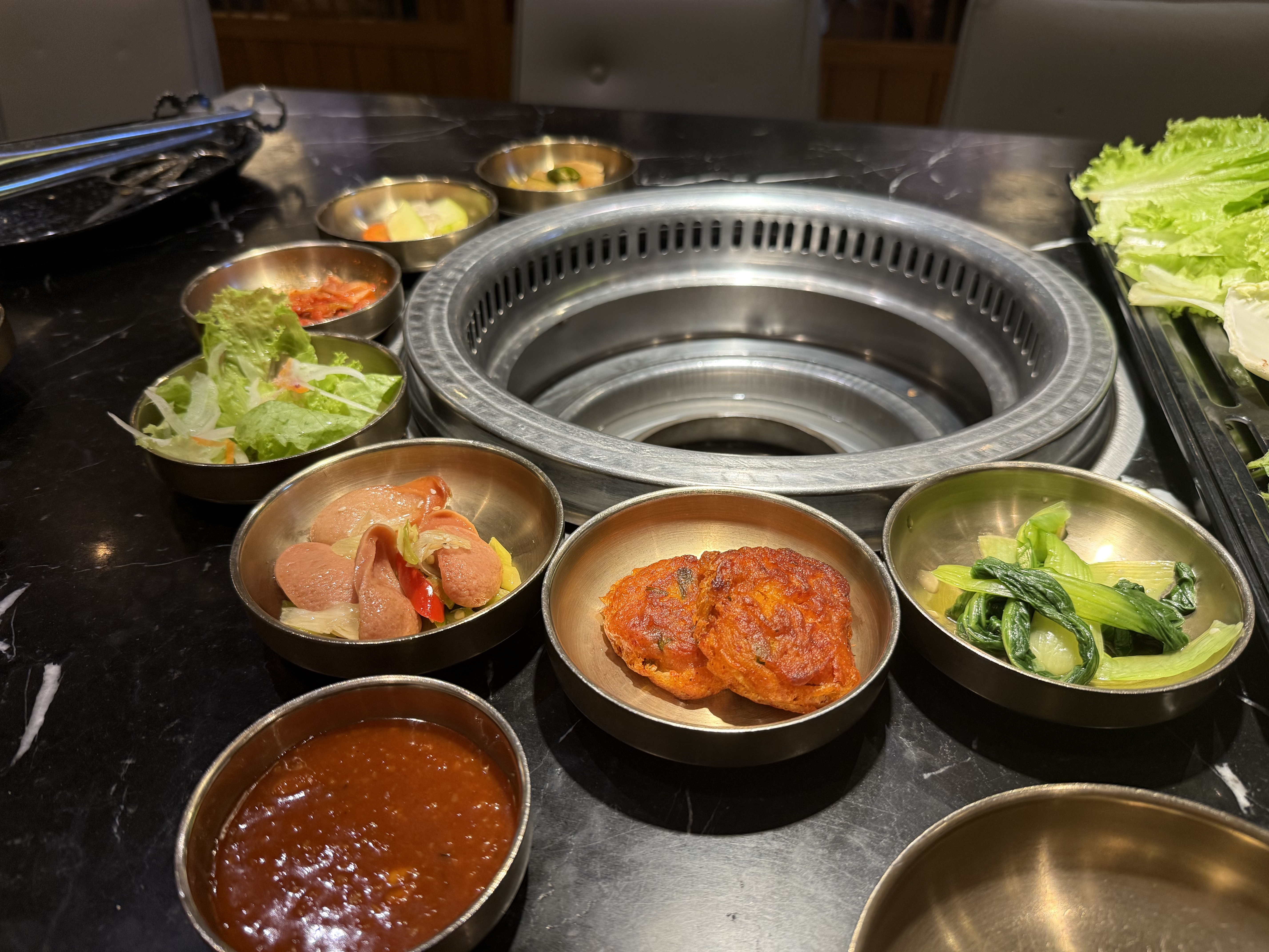 Banchan trong chén đồng quanh vỉ nướng — chi nhánh Vincom Đồng Khởi