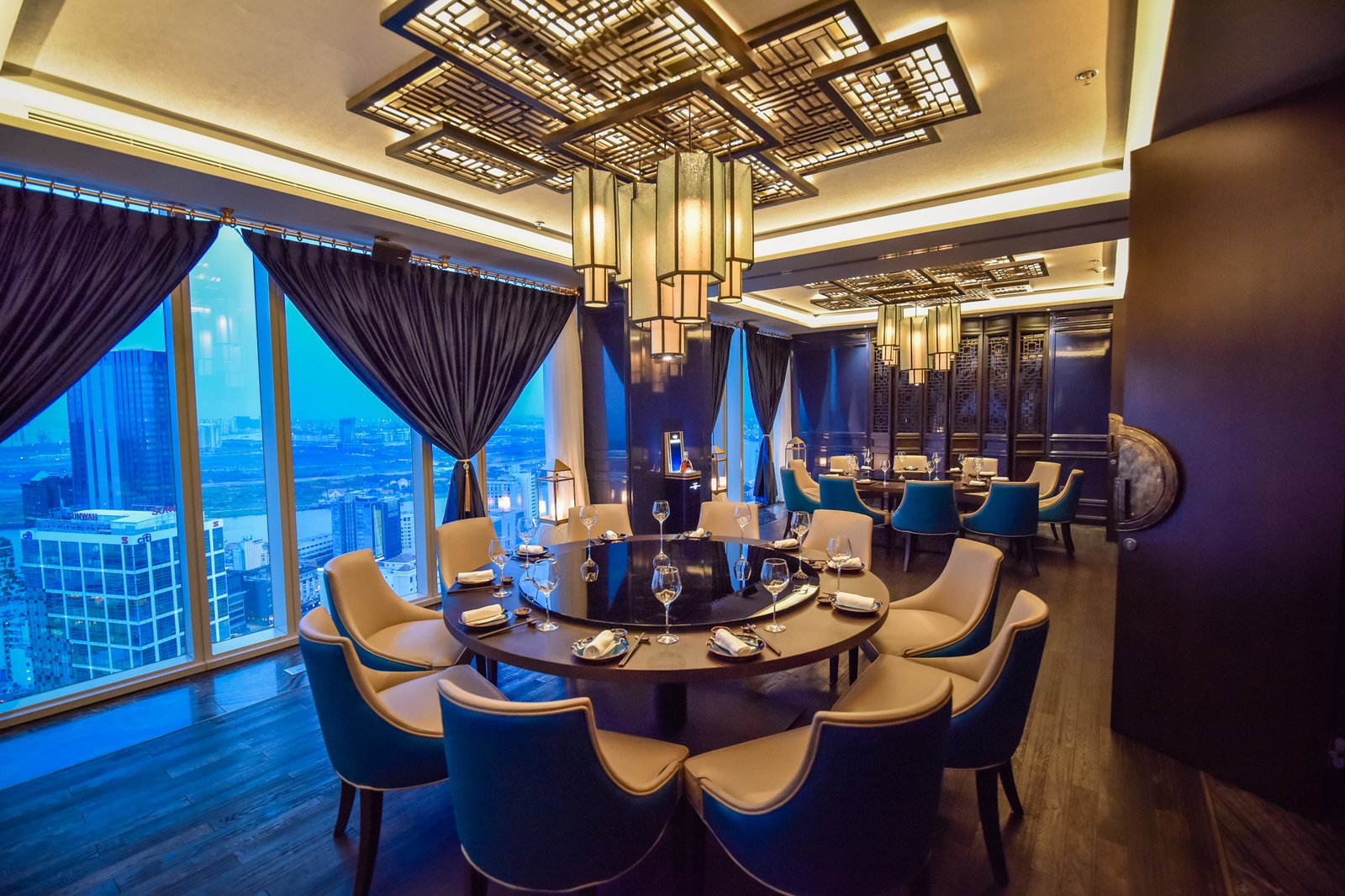 Phòng ăn Lai — bàn tròn xoay, đèn lồng lưới đồng, ghế bọc kem-xanh