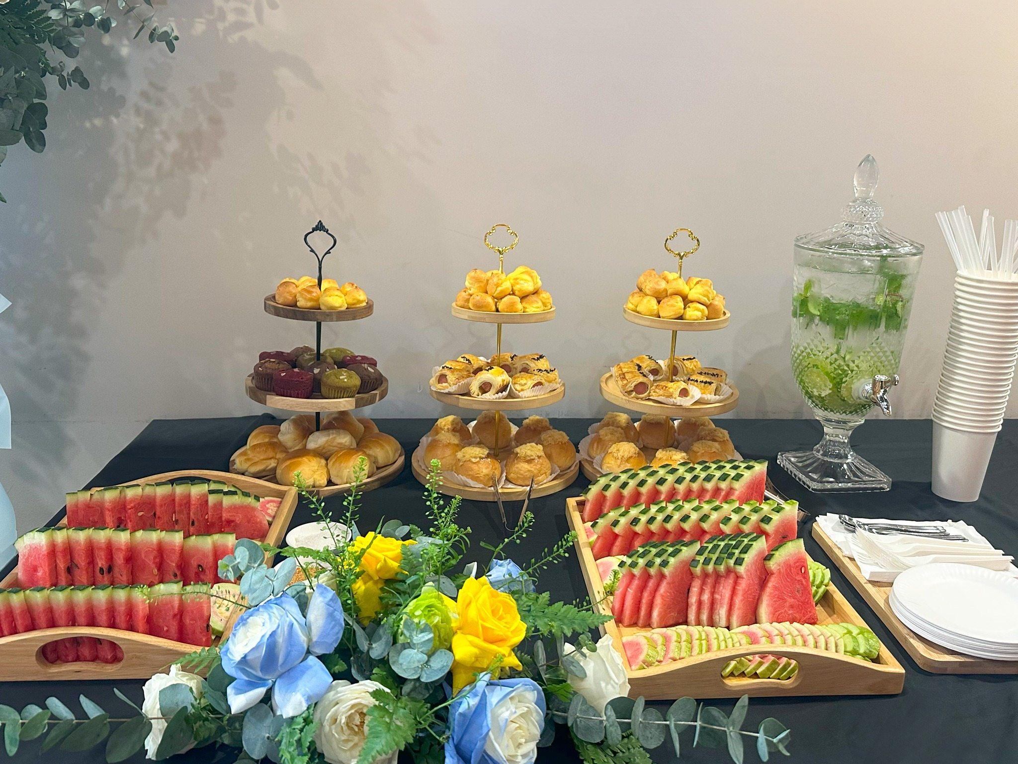 Bàn teabreak với khay bánh nhiều tầng, dưa hấu và hoa trang trí