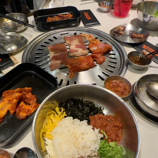 Table with a charcoal grill, bibimbap and side dishes