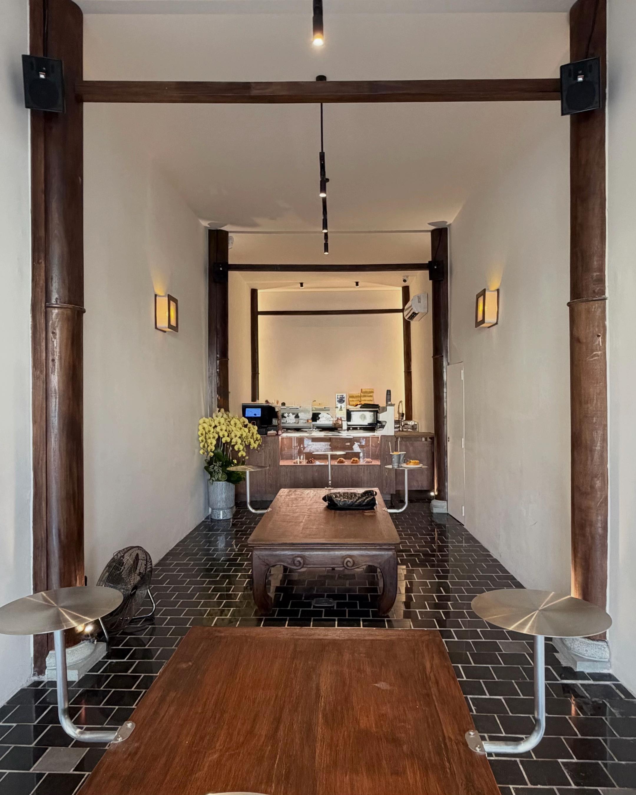Mille Mille Ben Thanh — the long room: communal wood table, black brick floor, wall sconces