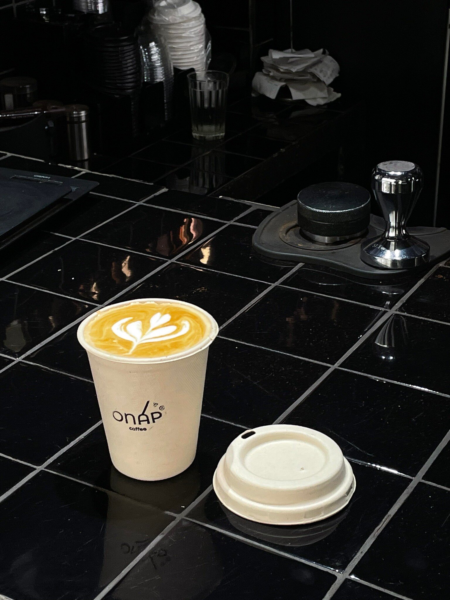 Ly giấy onap với latte art tulip trên quầy gạch đen