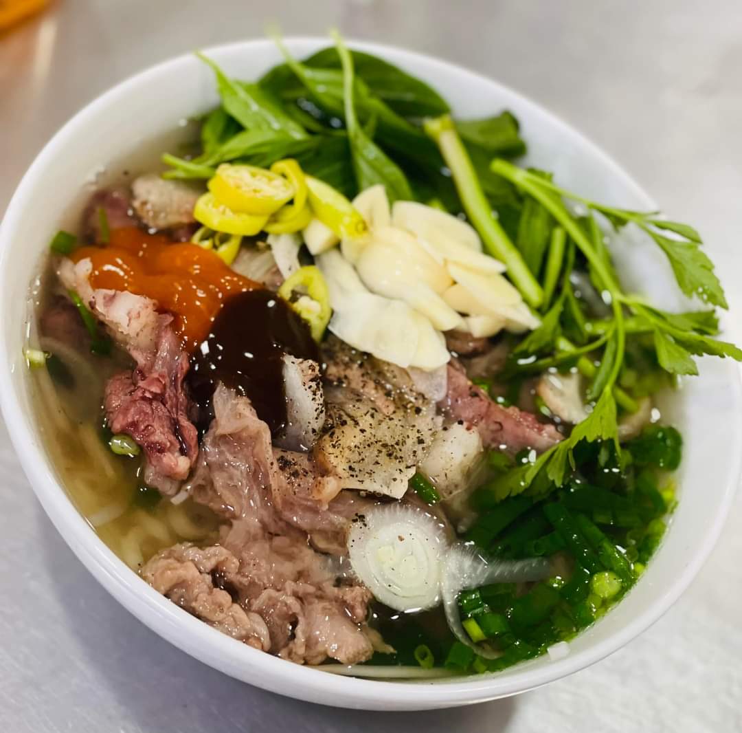 Tô phở bò Phở Bảo với hành lá trên bàn inox