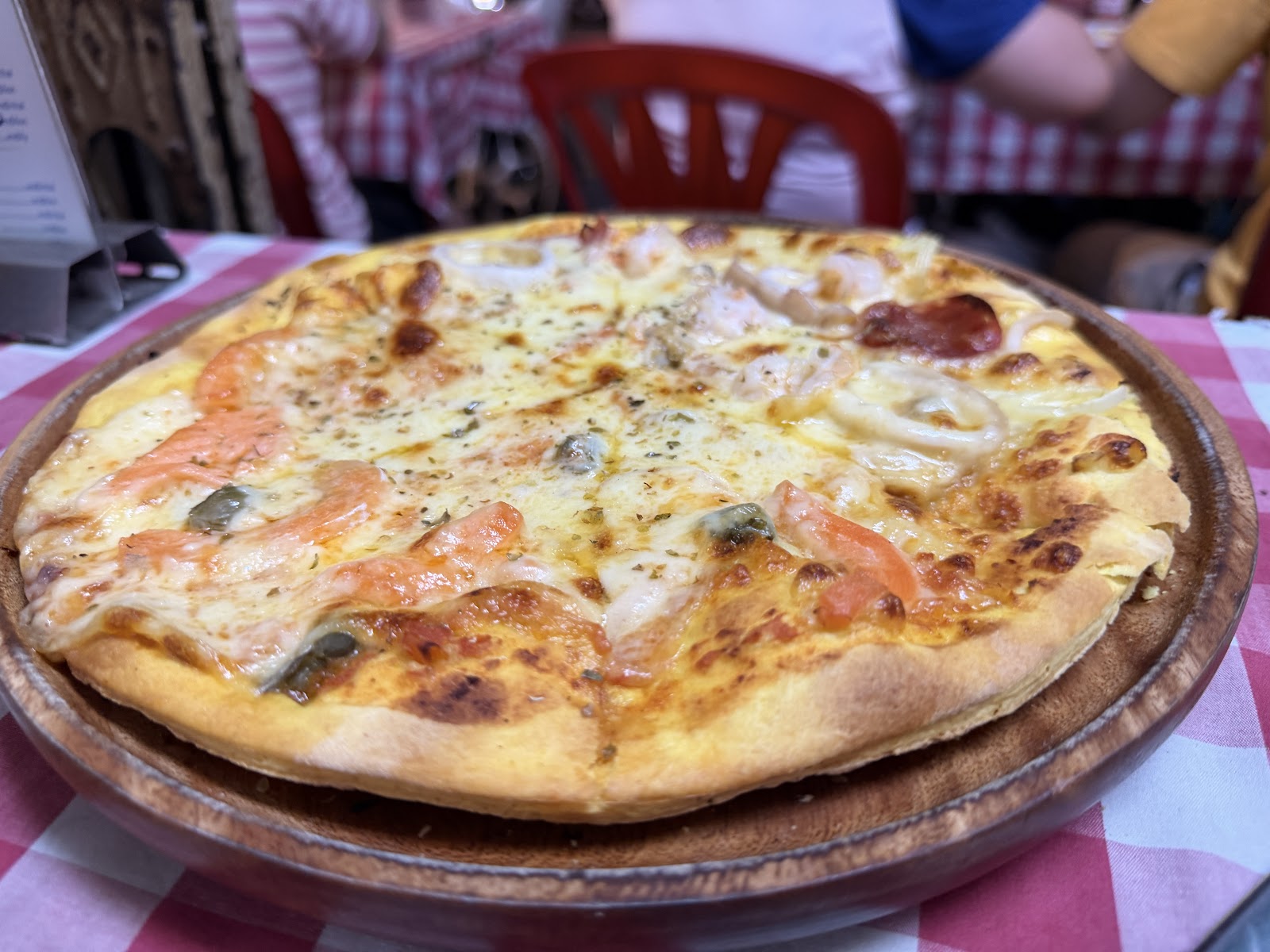 A seafood pizza on a wooden plate