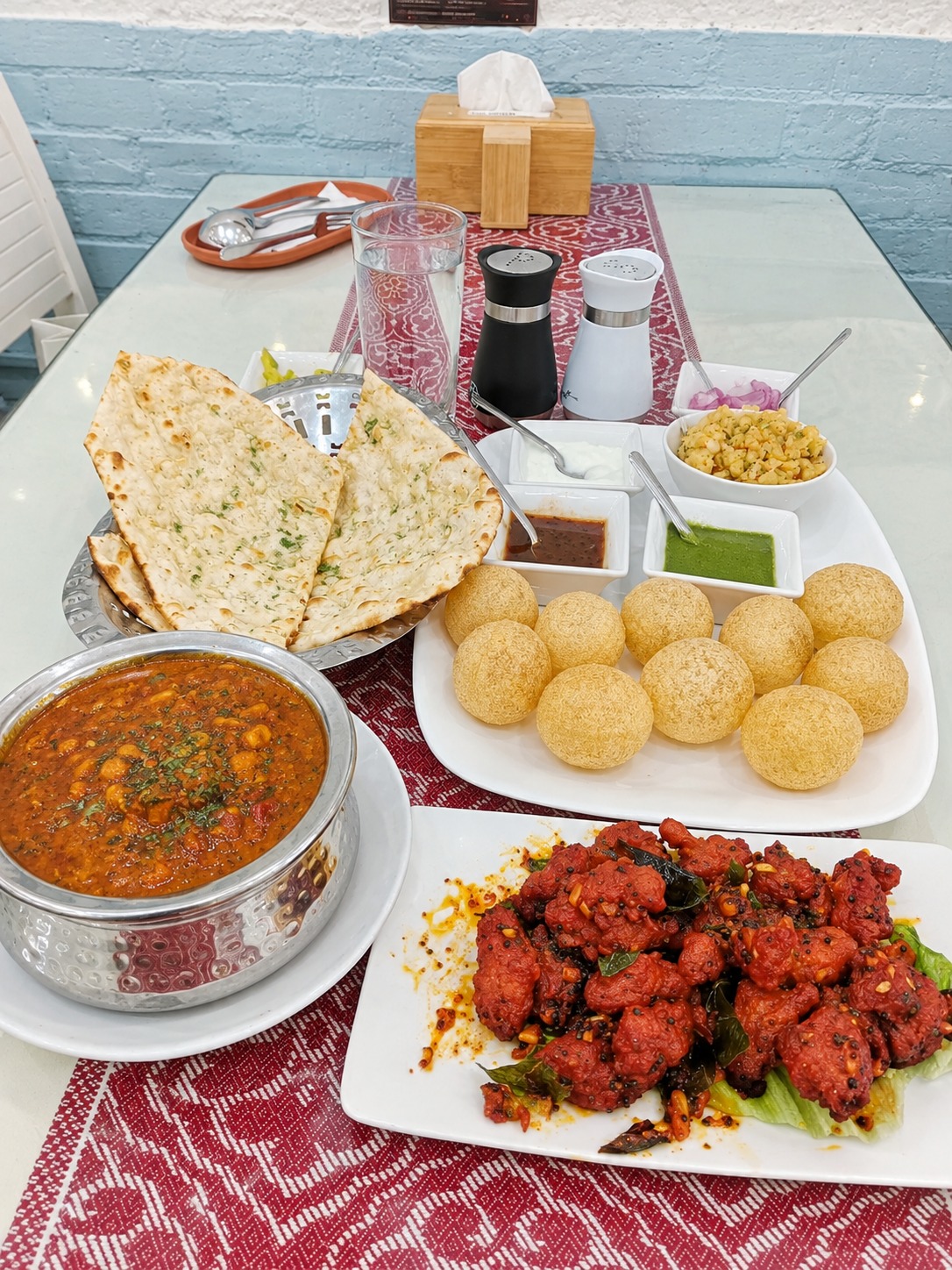 Bàn ăn với món nướng, bánh naan và chutney
