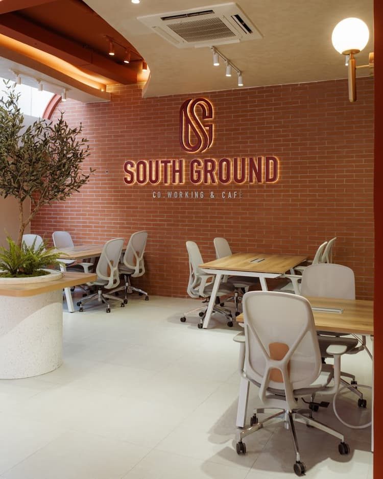 The coworking room with the glowing SG logo wall on red brick