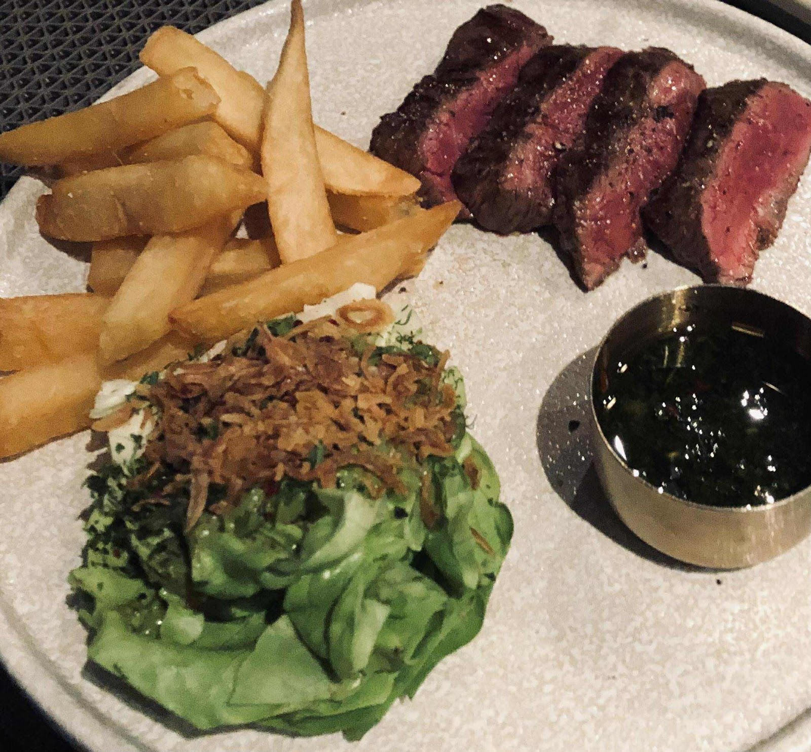 Steak cắt lát vừa chín, khoai chiên dày và salad hành phi