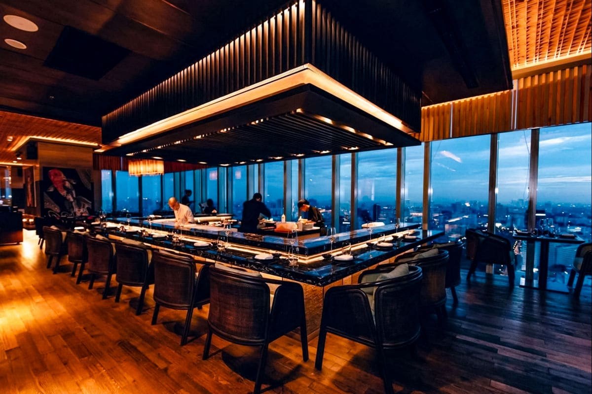 Towa's lounge at night — chefs behind the counter, the deep-blue city beyond the glass