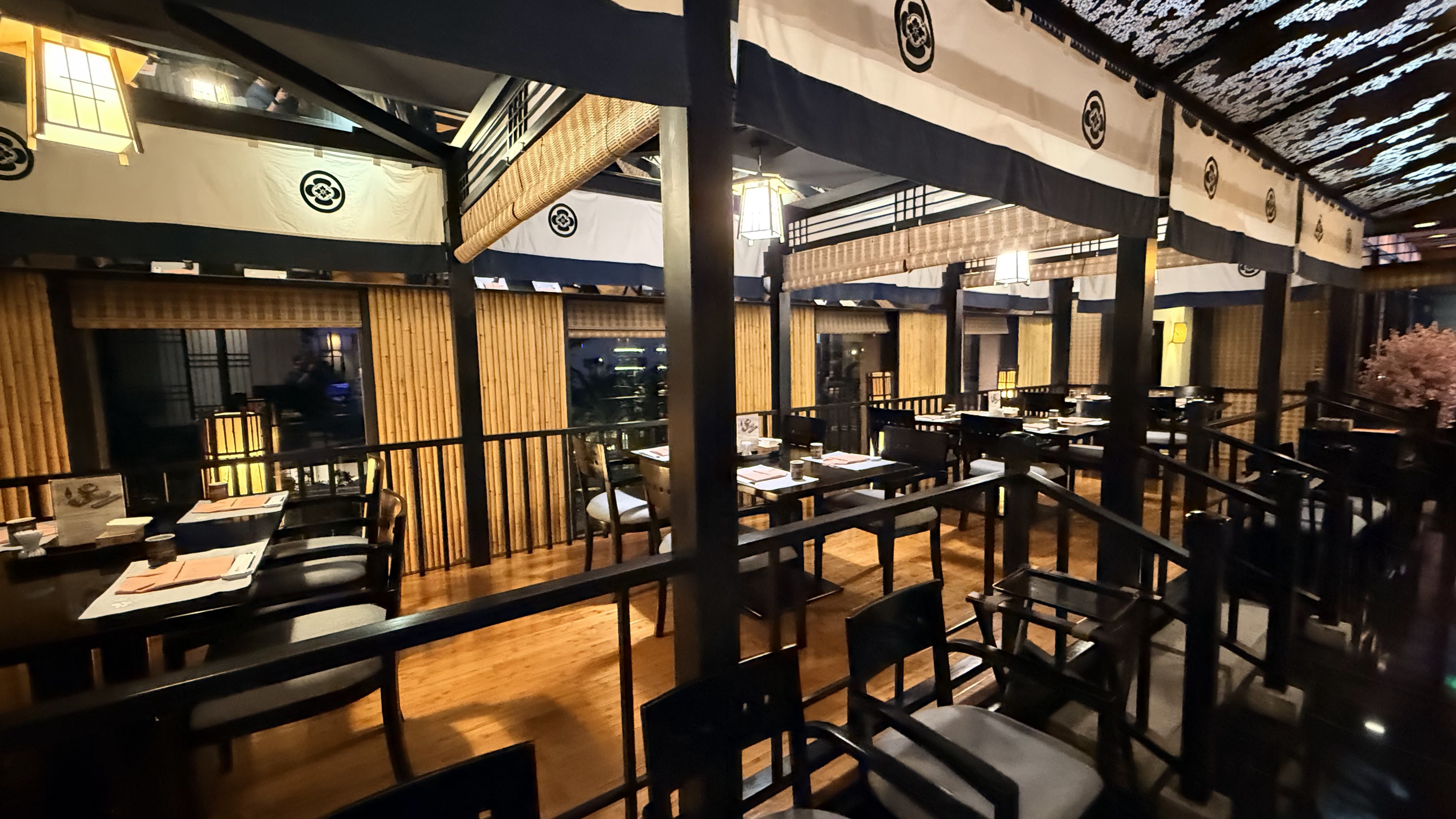 The Yoshino dining room — noren curtains with kamon crests, bamboo blinds, set tables