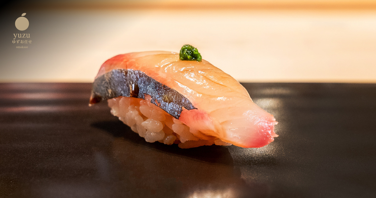 White-fish nigiri with wasabi on black ceramic